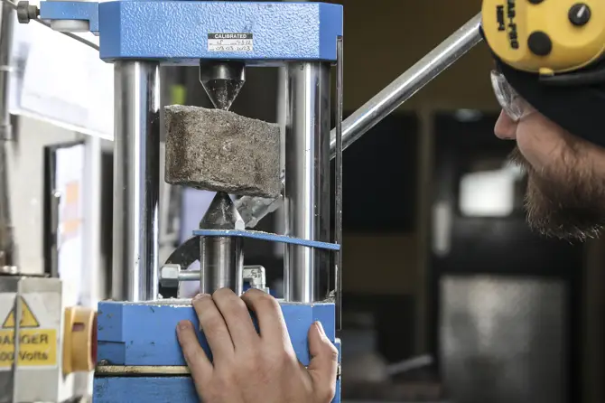 A Lab Technician overseeing a point load test of a rock sample A Lab Technician overseeing a point load test of a rock sample